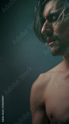 listen to oneself suffer Close-up studio portrait of a shirtless young man in profile with long tousled hair against a dark gradient background, showcasing a fit physique and contemplative expression