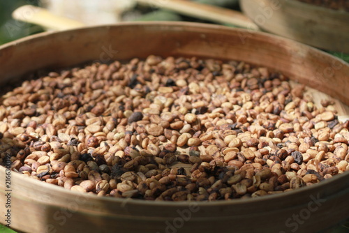 A wooden container filled with unroasted, sun-dried green coffee beans