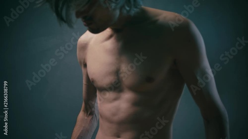 strength struggle Athletic adult man with shoulder-length hair posing with raised fists against a dark smoky background, showcasing strength and power under dramatic lighting