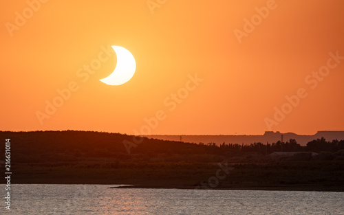 Canvastavla Telephoto view of crescent eclipsed sun setting over San Salvador reservoir, Spain