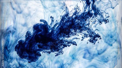 Indigo ink spreading in clear water. Abstract blue liquid cloud flowing in fluid.