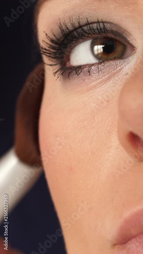 Makeup artist applying rouge to female face. Vertical video
