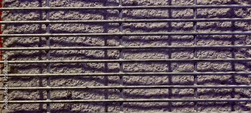 Foto Close-up of a textured concrete wall framed by evenly spaced horizontal metal bars