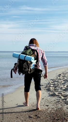 Man carrying backpack with camp equipment at sea. Vertical video