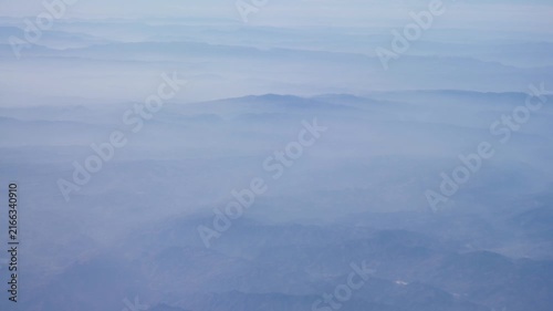 aerial natural view of mountain range over high plains of china near Tibet area with white cloud below in daytime from flying  airplane,natural aerial landscape view mountain range in winter time