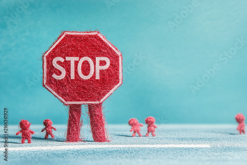 Red STOP sign with small human figures on blue background with copyspace.