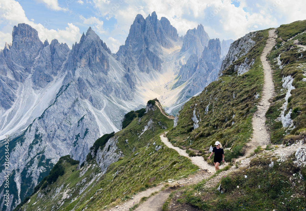 Fototapeta premium Young woman exploring hiking trail in Dolomites near Tre Cime Dolomites Italy
