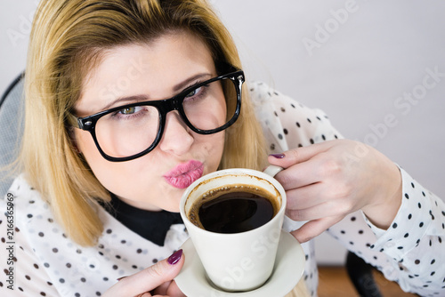 Happy woman at office drinking hot coffee