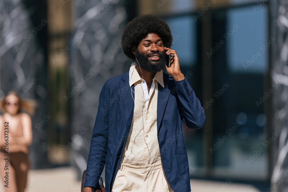 Fototapeta premium Bearded professional man walking outdoors with phone and briefcase for urban business background and banner design showing confident executive lifestyle