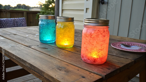 Glowing colorful mason jars on wooden table