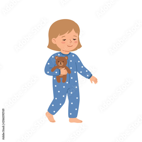 Cute little girl in blue star patterned pajamas walking while holding a small brown teddy bear toy