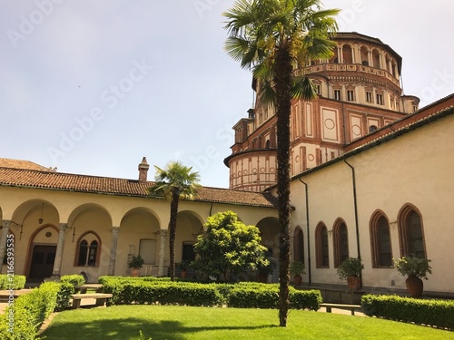 Church apse rising above the cloister garden in Milan in Santa Maria delle Grazie, Milan, Italy. The image presents architecture, heritage, and tourism in a clear, factual travel photograph.