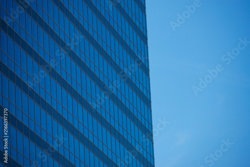 Cuadro en lienzo Modern glass architecture in Vienna with a reflective blue facade and strong geometric lines against a clear sky, offering generous negative space for corporate, architectural and business designs