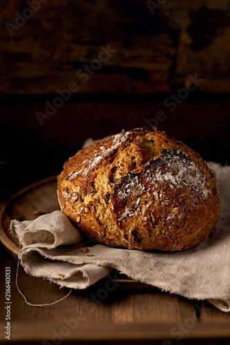 Artisan sourdough bread loaf on a rustic cloth and wooden tray