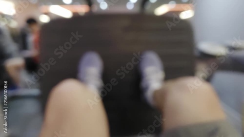 Blurred point of view shot of a person using a leg press machine at the gym. Out of focus legs and feet pushing against the equipment platform. Abstract fitness and workout background concept.