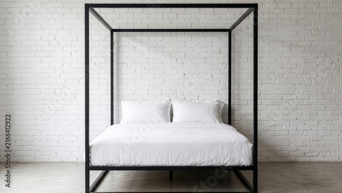 Modern industrial bedroom with black metal canopy bed and white brick wall