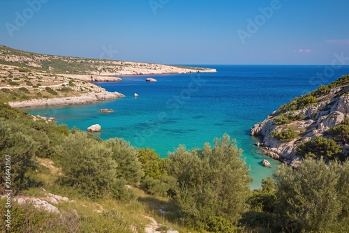 A tranquil beach scene featuring rocky terrain and abundant vegetation, captured from an overhead angle, showcasing the serene and peaceful coastal environment with vibrant blue and green t.