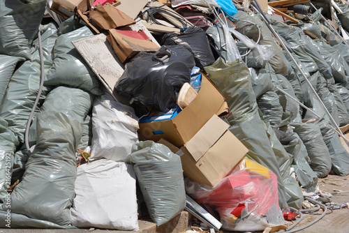 Фотография A massive pile of construction debris features green and white trash sacks mixed