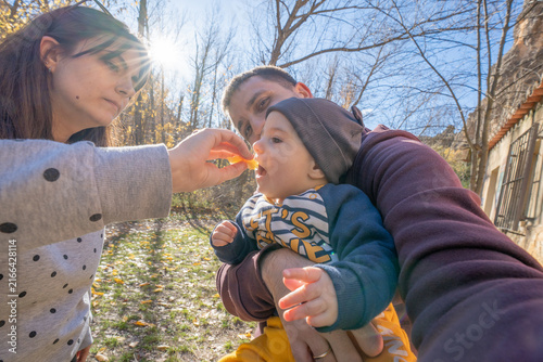Obraz na plátně Parents feeding baby fruit during outdoor trip