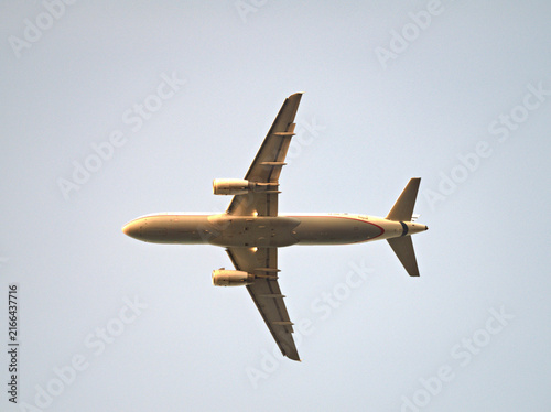 Принти на полотні A passenger jet aircraft in flight against a clear blue sky, viewed from below