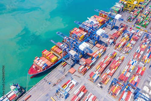 Aerial view of international cargo containers ship at industrial import-export port prepare to load containers with big container loader ship vessel at night. global transportation, logistic business.