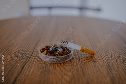 Cigarettes butts on ashtray at the wooden table.