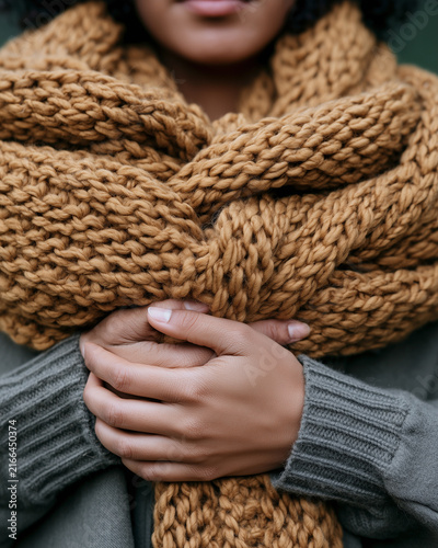 Close-up of hands wrapped in a warm knitted scarf