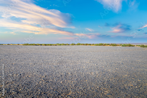 Vast gravel desert plain under a blue sky with colorful sunset clouds in Xinjiang, China