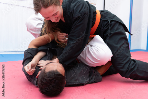 Canvastavla Young woman in black gi and orange belt practicing hapkido grappling and self-de