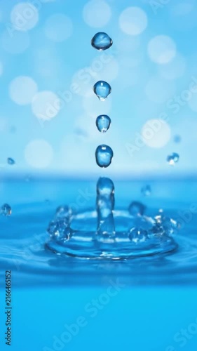 Water drop falling into blue liquid creating a perfect crown splash and ripples