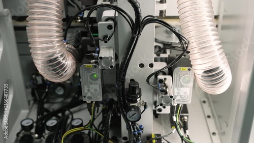 Close up view of complex industrial machinery with transparent hoses and black cables. Camera moves slowly to reveal inner workings and components. Focus on precision engineering and technology