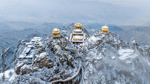 Snow-covered Golden Summit temples on Laojun Mountain in Henan, China, surrounded by dramatic winter mountain scenery.