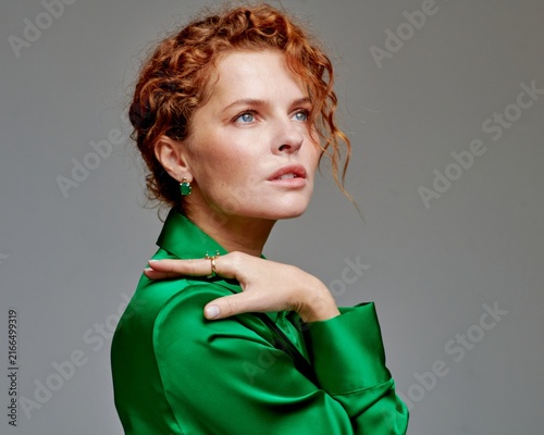 Foto Elegant Portrait of a Woman with Curly Hair in a Green Silk Outfit Displaying So