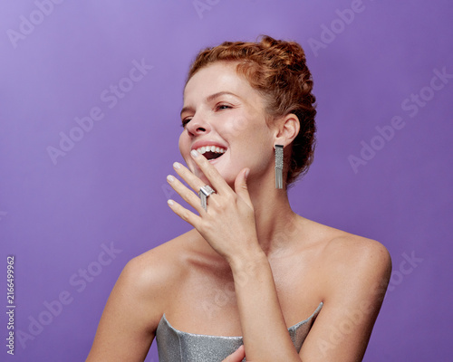 Foto Elegant Woman Adorned with Stunning Jewelry Laughs Joyfully Against a Purple Bac