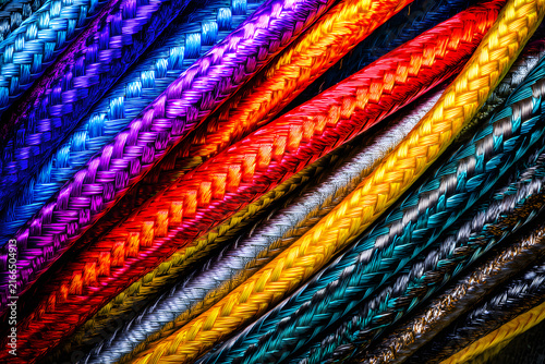 Close-up of colorful braided ropes in a diagonal pattern, featuring a spectrum of vibrant and metallic hues with detailed texture.
