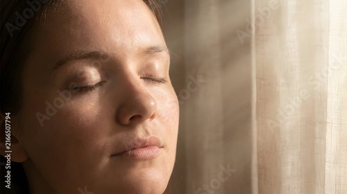 Peaceful Woman Relaxing with Closed Eyes Near Window in Natural Light
