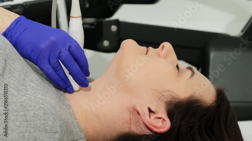 Physician hand guides sensor over patient neck in clinic closeup. Woman posture shows comfort and cooperation during examination in hospital