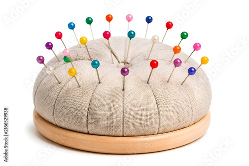 Obraz na płótnie Round Pincushion With Multicolored Pins Evenly Arranged On White Background For