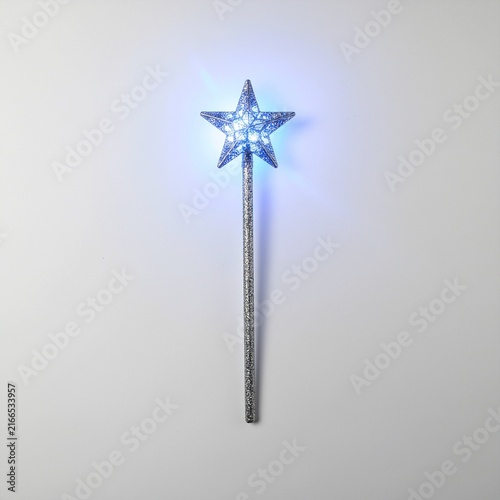 Magical silver star wand with glowing blue lights on grey