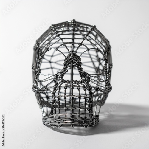 Handmade wire skull sculpture art on white table studio