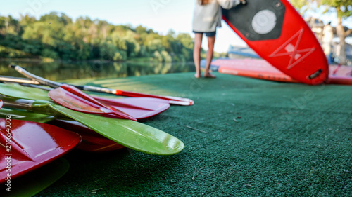 Paddleboards and paddles ready for use on a calm river at sunset