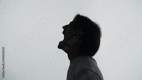 Silhouette of a man shouting in rage during a loud emotional outburst