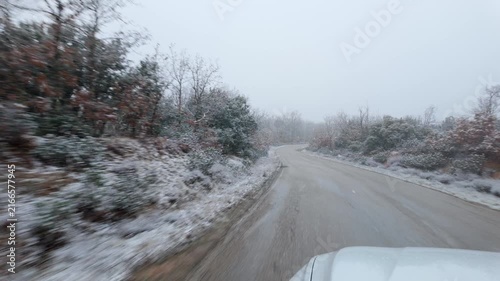 Moving along a winding rural road through snow covered woodland during steady winter snowfall
