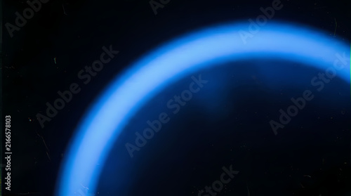 A bright blue ring glows against a dark, grainy background.