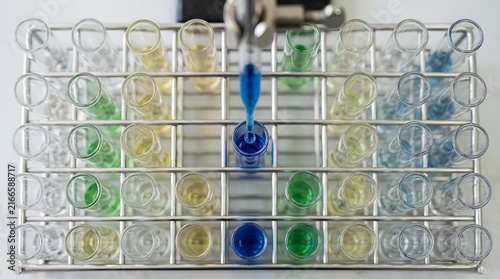 Pipette dispensing blue chemical liquid into a test tube inside a metal rack