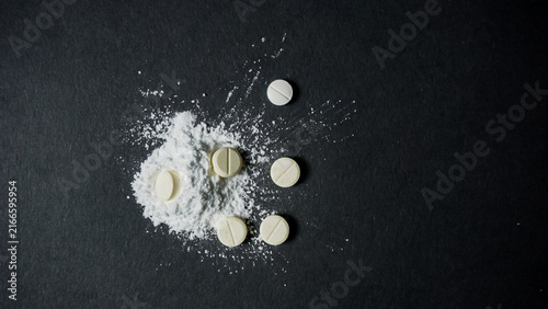 Foto Top view of some white pills with powder form on black surface