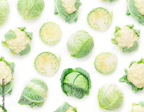 Fresh whole and cut green cabbages alongside white cauliflowers are carefully arranged in a beautiful pattern on a clean white background, showcasing healthy natural produce