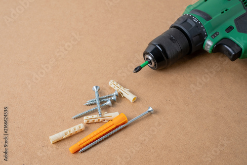 Cordless drill with screws and plastic dowels on cardboard