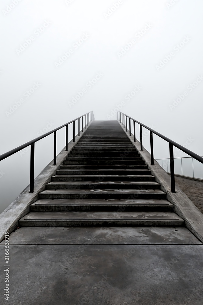 Fototapeta premium Concrete staircase ascending upward into dense white foggy atmosphere