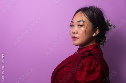 Принти на полотні Asian Woman with makeup and floral hair accessory posing in red dress, purple st